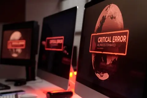 Monitors displaying critical error screens in a dark room