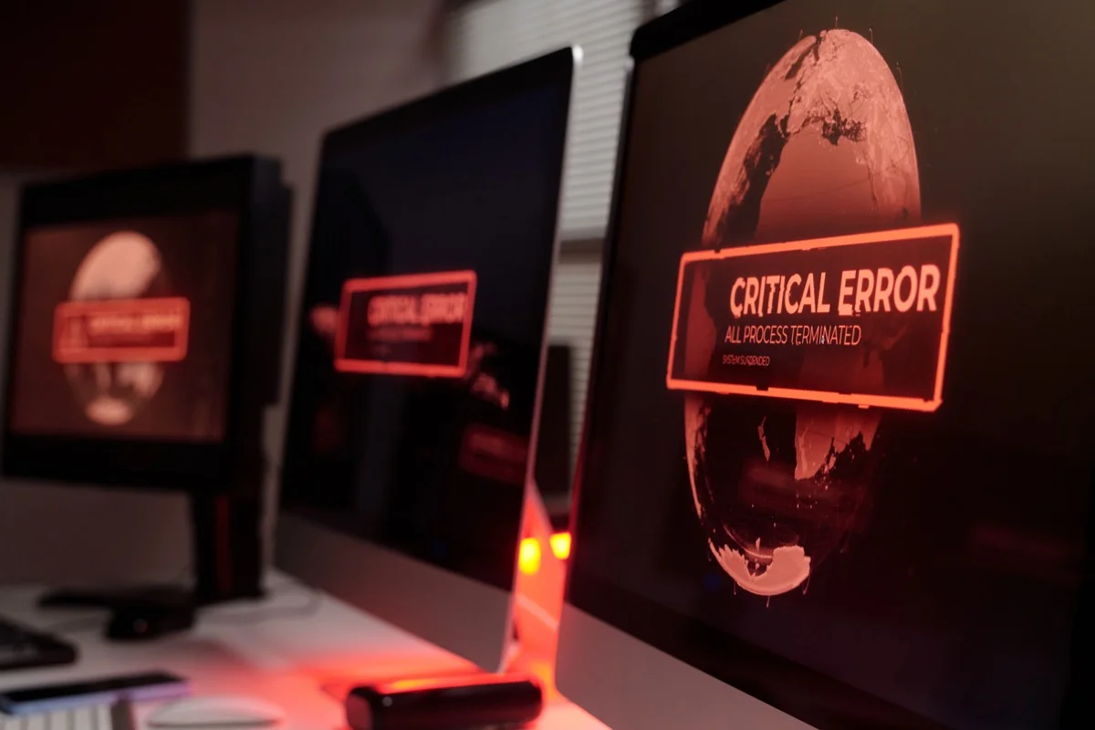 Monitors displaying critical error screens in a dark room